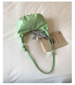 Detail of mint green dumpling bag with fashion embossing and silver starfish charm