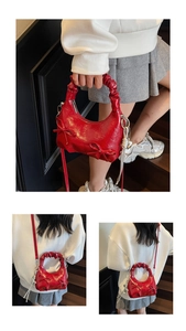 Detail of red glossy bow shoulder bag with ruched handle and silver hardware