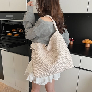 Close-up of cream woven tote bag featuring thick knit texture and star-shaped charm