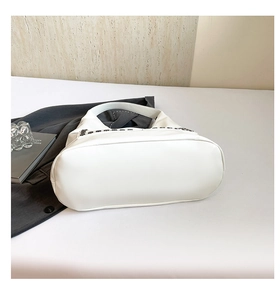 Detail of white leather tote bag with dark metal rivets and spacious bottom
