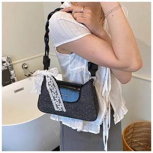 Détail du sac à bandoulière noir scintillant avec nœud en dentelle blanche et anse
