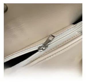 Detailed close-up of the smooth silver zipper and fine stitching on a beige leather tote