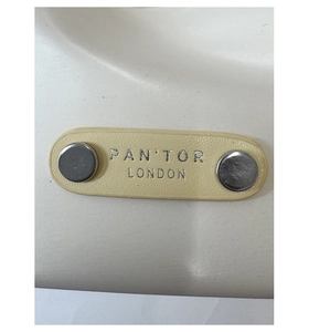 Gros plan d'une étiquette en cuir beige avec rivets argentés et texte de marque gravé