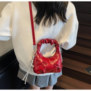 Detail showing red glossy patent leather handbag with bow accents and star charm
