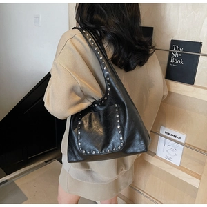 Vue arrière d'un mannequin portant un sac hobo en cuir ciré noir avec rivets argentés