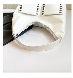 Close-up of white hobo bag with dark hexagonal metal rivets and premium leather texture