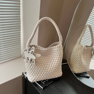 Detail of white hand-woven tote bag with star charm and metallic ring buckle texture