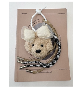 Détail d'un pendentif chien en peluche avec nœud en dentelle et sangles tissées sur un livre