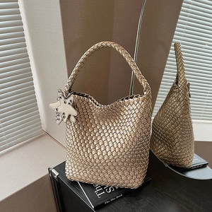 Detail of champagne gold hand-woven tote bag with star charm and metallic leather texture