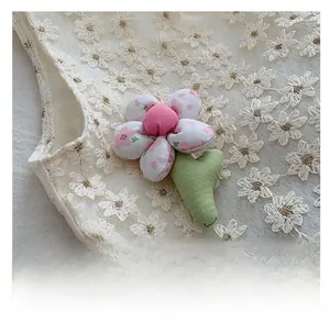Close-up of handmade pink floral fabric flower with green leaf on white lace
