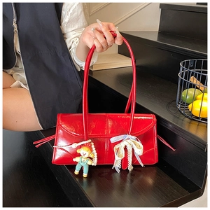 Detail of red shiny faux leather tote bag featuring lace bow and cute doll charm