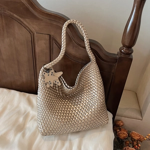 Close-up of champagne woven tote bag featuring a leather star charm and metallic texture
