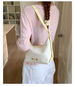 Détail du sac sous l'aisselle crème minimaliste avec bandoulière réglable et plaque métal