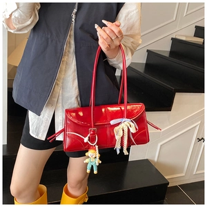 Detail of red glossy tote bag with lace bows, pearl chain, and cute doll pendant charms