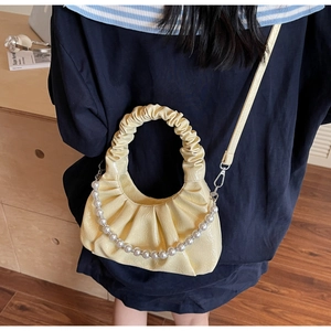Close-up of cream yellow pleated cloud bag with elegant pearl chain and strap