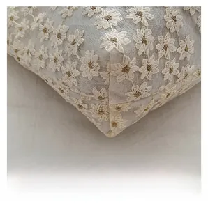 Close-up of white daisy embroidery with golden metallic stitching on canvas tote bag
