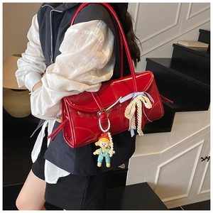 Detail of red patent leather shoulder bag with blue plaid lace bow and doll charm
