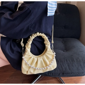 Detail view of light yellow cloud bag featuring ruched PU leather and pearl chain strap