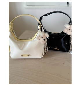 Détail de sacs demi-lune en cuir verni brillant avec logo en métal et breloque ours peluche