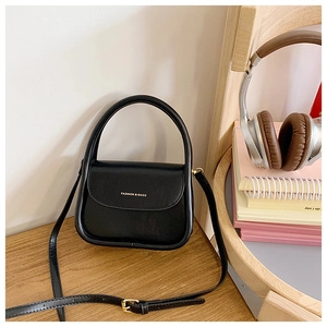 Close-up of black leather crossbody bag with top handle and gold fashion lettering