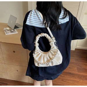 Close-up of cream ruched cloud bag with elegant pearl chain and thin crossbody strap