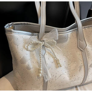 Dettaglio della borsa tote jacquard floreale con strass e ciondolo a fiocco di perle