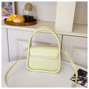 Detail view of cream mini square bag with leather handle and adjustable shoulder strap