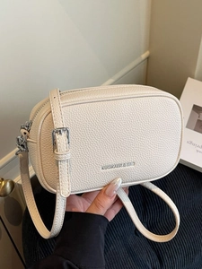 Cream white crossbody camera bag in lychee texture leather with silver chain strap and logo