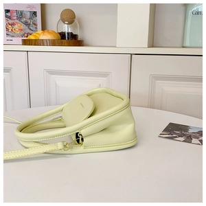 Detail of minimalist pale yellow PU leather handbag with sleek top handle and slim strap