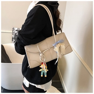 Detail of cream tote bag featuring lace ribbon, bow, and cute cartoon girl pendant