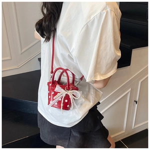 Side view of mini red polka dot bucket bag with white lace bow and pearl charm decoration