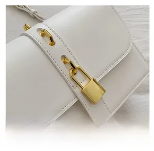 Detail of white structured leather bag with gold lock and metal eyelet shoulder strap