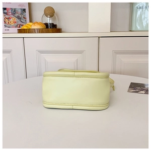 Detailed base view of a pastel yellow leather crossbody bag showing reinforced stitching