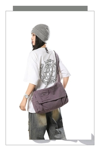 Detailed view of the large purple canvas messenger bag showing the front flap and side pocket