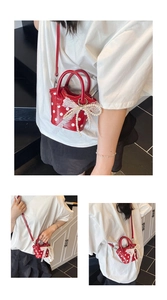 Close-up of red polka dot mini bucket bag featuring lace bow and pearl charm
