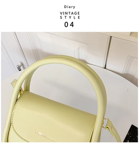 Detailed view of pale green handbag featuring FASHION & BAGS gold lettering and metal rings