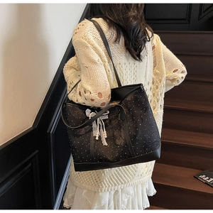 Dettaglio della borsa tote floreale con fiocco in pizzo e perla su modella