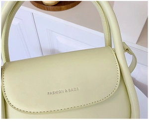 Close-up of a light green small square bag with Fashion & Bags logo and fine stitching