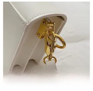 Detail of premium gold metal clasp and precise stitching on white leather handbag