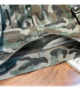 Close-up of the smooth black metal zipper on a woodland camouflage canvas messenger bag