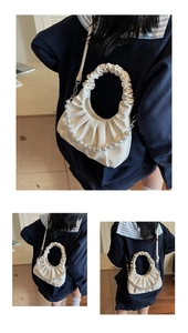 Detail of white pleated cloud bag with elegant pearl chain and soft scrunched handle strap
