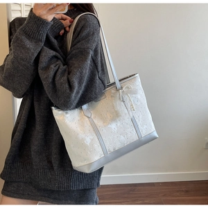 Borsa tote bianca con ricamo a farfalla e ciondolo di perle mostrata in un selfie allo specchio