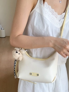Sac à bandoulière demi-lune crème minimaliste avec breloque ours et ruban élégant