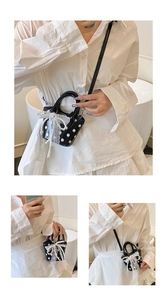 Close-up of mini polka dot bucket bag featuring white lace bow and pearl handle details