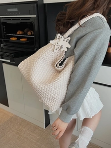 Handwoven cream tote bag with star charms worn by a model in a natural kitchen setting