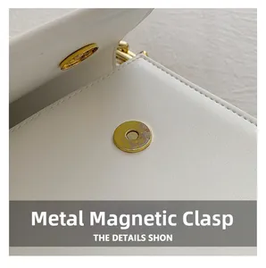 Detailed macro view of the golden magnetic buckle and stitching on the white leather bag