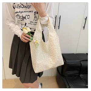 Close-up of white floral lace tote bag featuring daisy pendant and petal embroidery