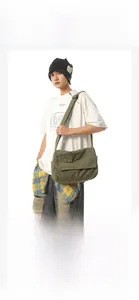 Olive green canvas messenger bag worn by male model to show large capacity and fit