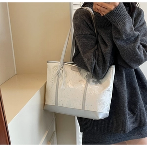Dettaglio della borsa tote bianca testurizzata con ciondolo a fiocco di perle e finiture