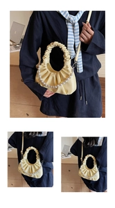 Detail view of yellow ruched cloud bag featuring decorative pearl chain and leather texture